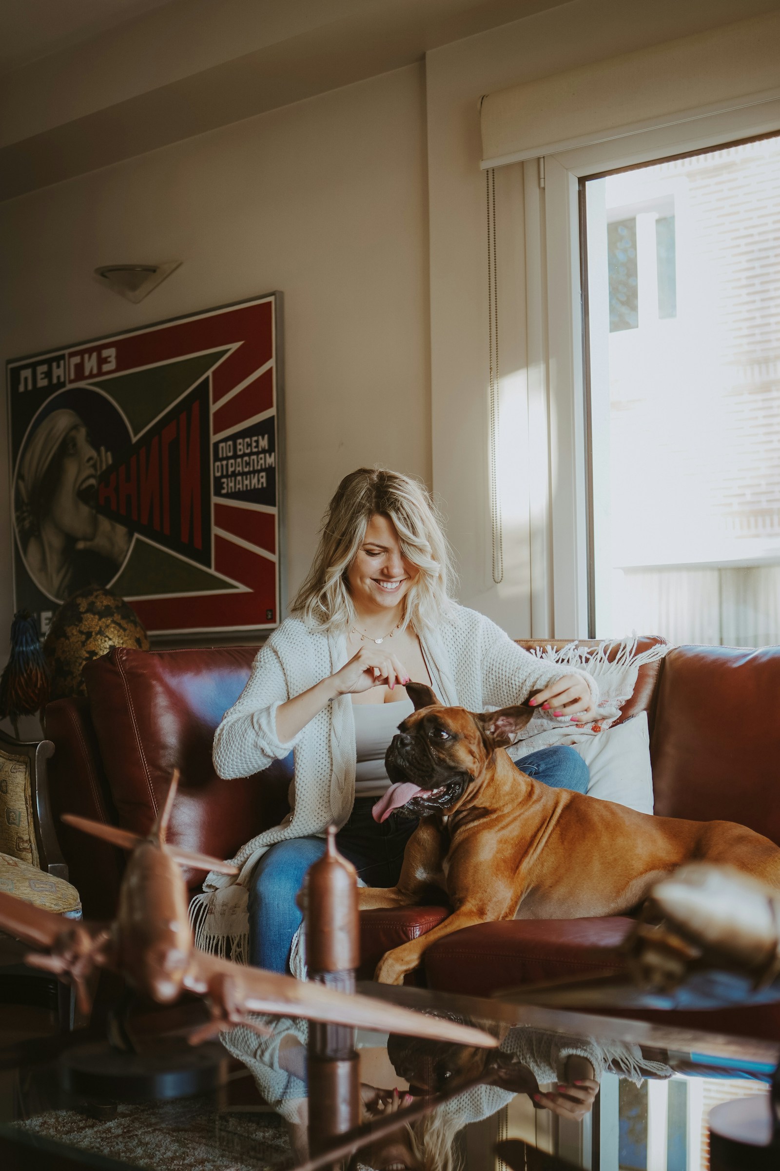 A woman smiling on a sofa with her boxer dog